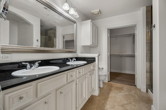 bathroom featuring a shower with shower door, toilet, vanity, and tile patterned floors