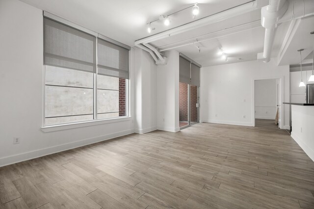 unfurnished living room featuring hardwood / wood-style flooring and track lighting