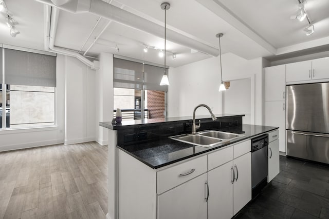 kitchen with sink, appliances with stainless steel finishes, an island with sink, track lighting, and white cabinetry