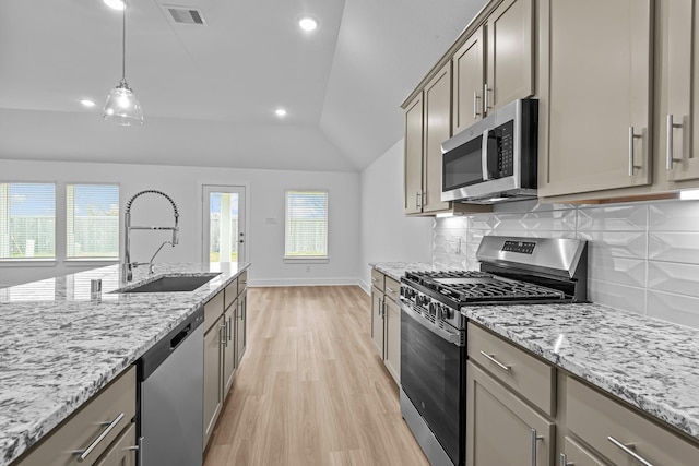 kitchen featuring sink, hanging light fixtures, stainless steel appliances, a wealth of natural light, and vaulted ceiling