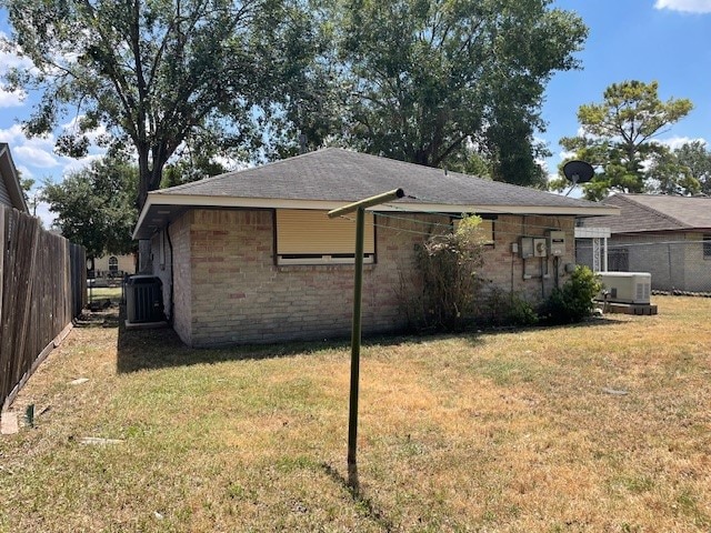 back of house featuring central air condition unit and a lawn