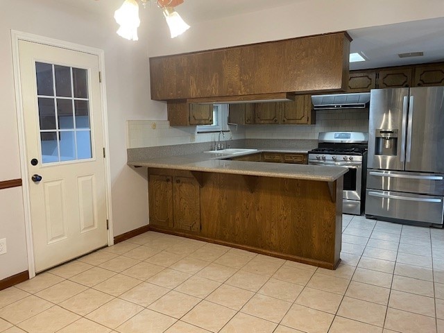 kitchen featuring backsplash, kitchen peninsula, exhaust hood, and appliances with stainless steel finishes