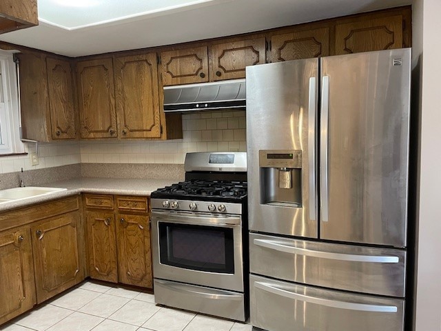 kitchen featuring light tile patterned flooring, sink, appliances with stainless steel finishes, and decorative backsplash