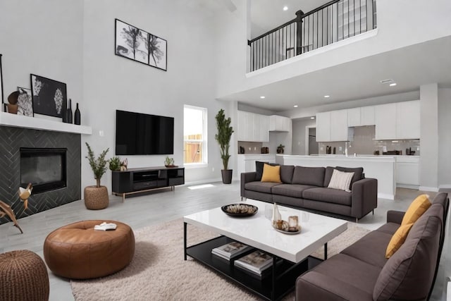 living room with a fireplace, light hardwood / wood-style floors, and a high ceiling