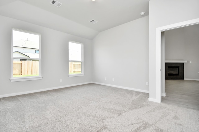 unfurnished room featuring plenty of natural light, light hardwood / wood-style flooring, and lofted ceiling