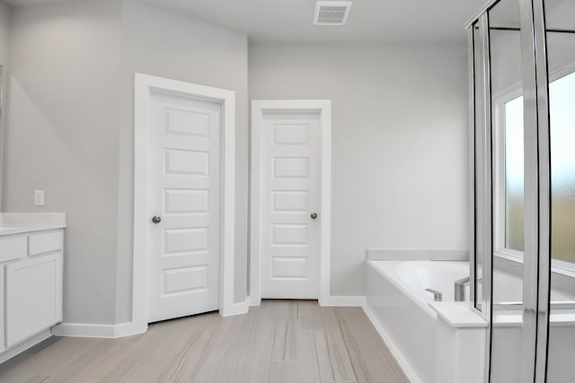 bathroom with tile patterned floors, a washtub, and vanity