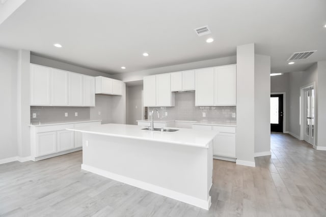 kitchen with a kitchen island with sink, sink, light hardwood / wood-style floors, and white cabinetry