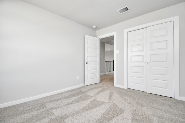 unfurnished bedroom with light carpet and a closet