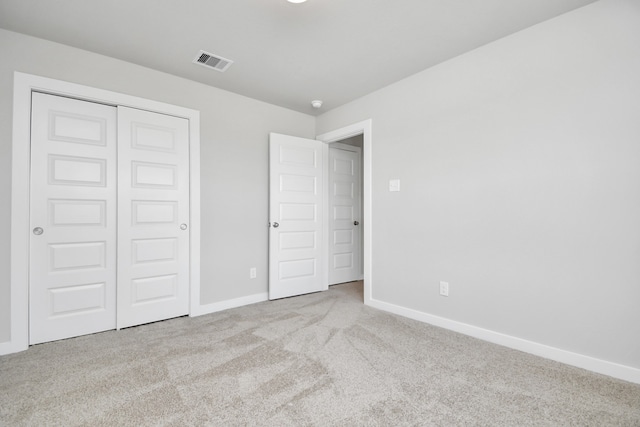 unfurnished bedroom with a closet and light colored carpet