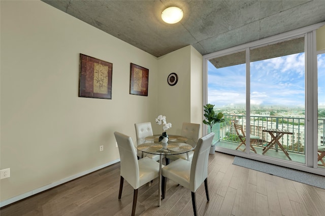 dining area with wood-type flooring and a wall of windows