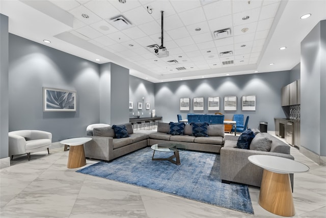 tiled living room featuring a raised ceiling, ceiling fan, and a drop ceiling