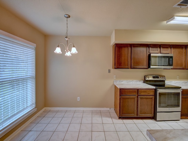 kitchen featuring light tile patterned floors, stainless steel appliances, a notable chandelier, and decorative light fixtures