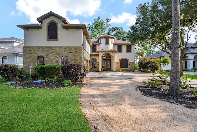 mediterranean / spanish-style house with a front yard and french doors