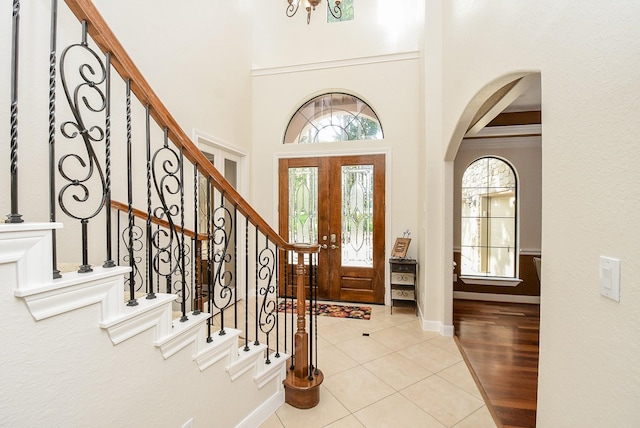 foyer entrance featuring a high ceiling, light wood-type flooring, and crown molding