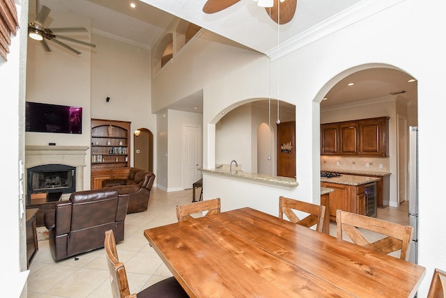 dining area with wine cooler, high vaulted ceiling, light tile patterned floors, ceiling fan, and ornamental molding