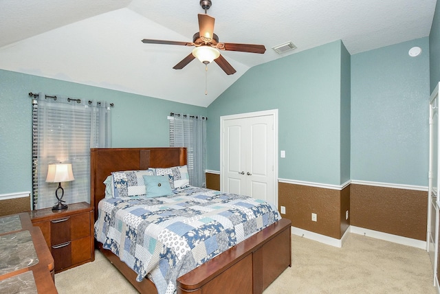 bedroom featuring vaulted ceiling, light carpet, ceiling fan, and a closet