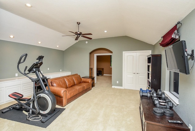 exercise room with lofted ceiling, ceiling fan, light colored carpet, and a textured ceiling