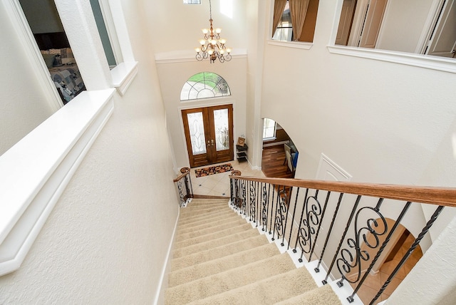 staircase with tile patterned floors and a notable chandelier