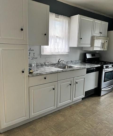 2410 Milby St, Houston, TX 77004 - kitchen with a sink, stainless steel appliances, light countertops, and white cabinets
