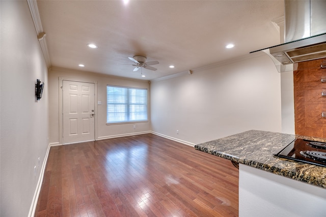 kitchen featuring dark stone counters, hardwood / wood-style floors, ornamental molding, and ceiling fan