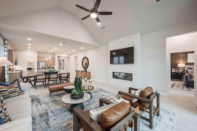 living room with ceiling fan, a stone fireplace, high vaulted ceiling, and sink