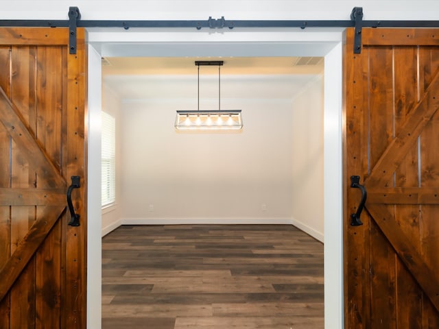 dining room with a barn door, dark wood-type flooring, and crown molding