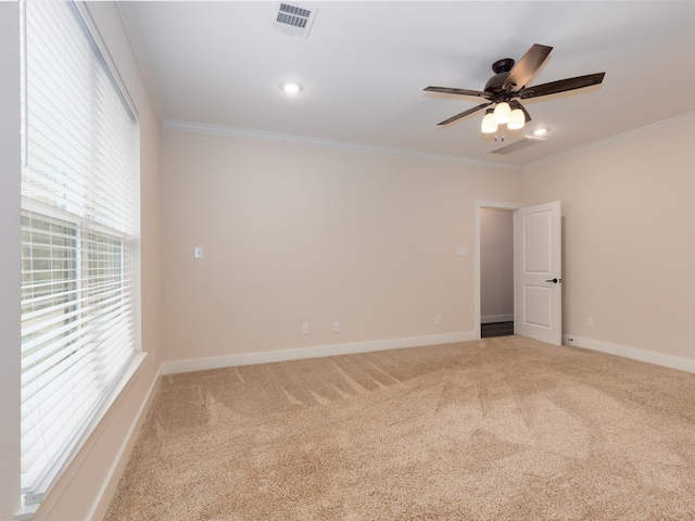 empty room with a wealth of natural light, carpet flooring, ceiling fan, and crown molding