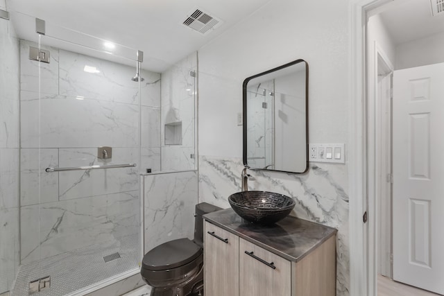 bathroom with tile walls, vanity, tiled shower, and toilet