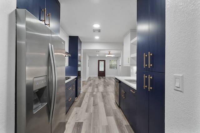 kitchen featuring light hardwood / wood-style flooring, appliances with stainless steel finishes, and blue cabinetry