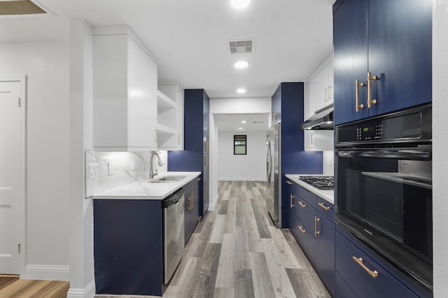 kitchen with light hardwood / wood-style flooring, blue cabinets, wall chimney exhaust hood, and stainless steel appliances