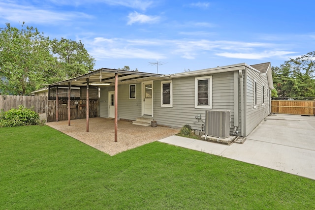 rear view of property featuring central AC unit and a lawn