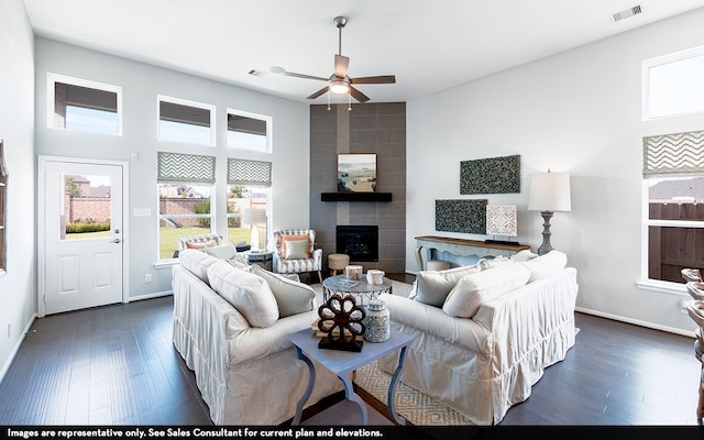 living room with a tiled fireplace, dark hardwood / wood-style flooring, and ceiling fan