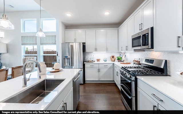 kitchen with dark hardwood / wood-style floors, stainless steel appliances, sink, decorative light fixtures, and white cabinetry