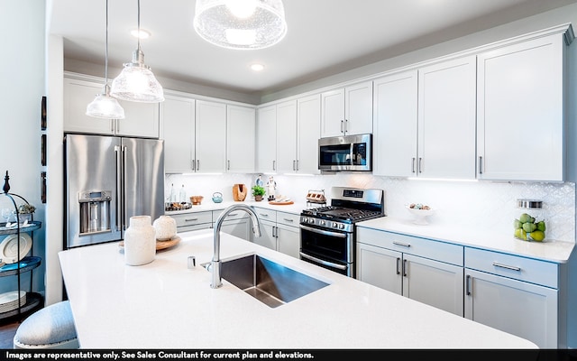 kitchen with appliances with stainless steel finishes, sink, hanging light fixtures, white cabinetry, and decorative backsplash