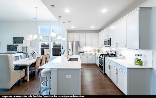 kitchen featuring appliances with stainless steel finishes, sink, hanging light fixtures, white cabinetry, and dark wood-type flooring