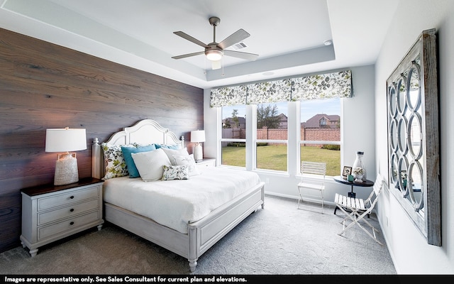 bedroom featuring wooden walls, carpet flooring, a raised ceiling, and ceiling fan