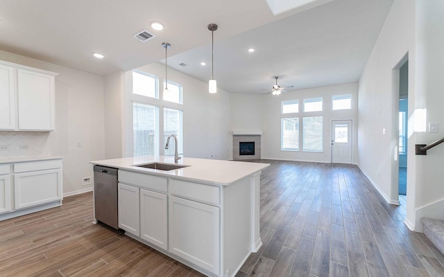 kitchen with white cabinetry, sink, stainless steel dishwasher, and light wood-type flooring