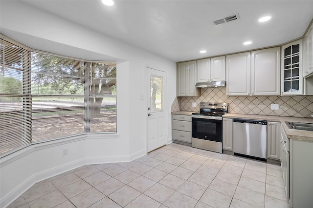 kitchen featuring appliances with stainless steel finishes, tasteful backsplash, light tile patterned floors, and sink