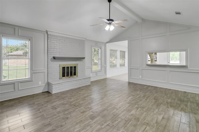 unfurnished living room featuring wood-type flooring, a brick fireplace, ceiling fan, and a healthy amount of sunlight