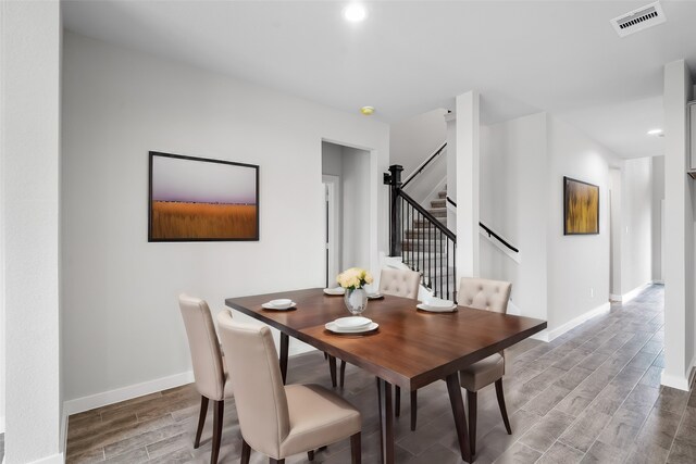 dining room featuring stairway, wood finished floors, visible vents, and baseboards