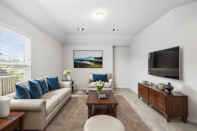 living area with vaulted ceiling, baseboards, visible vents, and light colored carpet