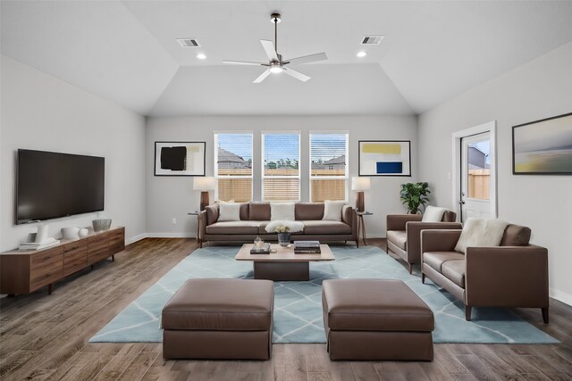 living area with lofted ceiling, wood finished floors, visible vents, and baseboards