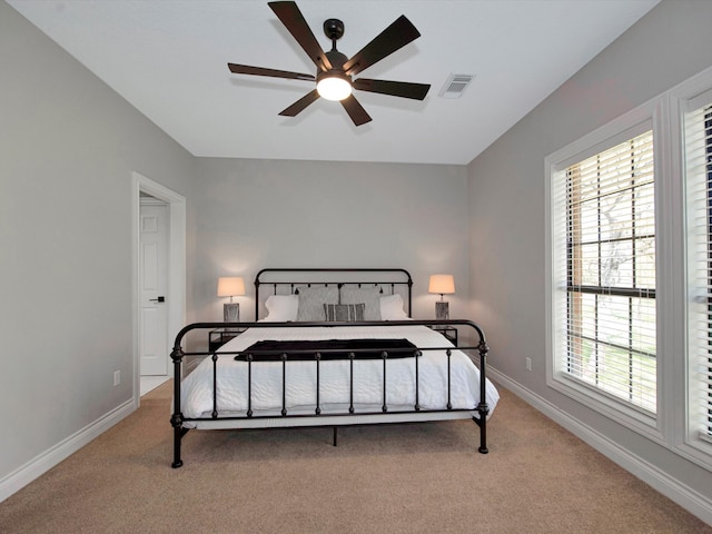 bedroom with ceiling fan, light carpet, and multiple windows