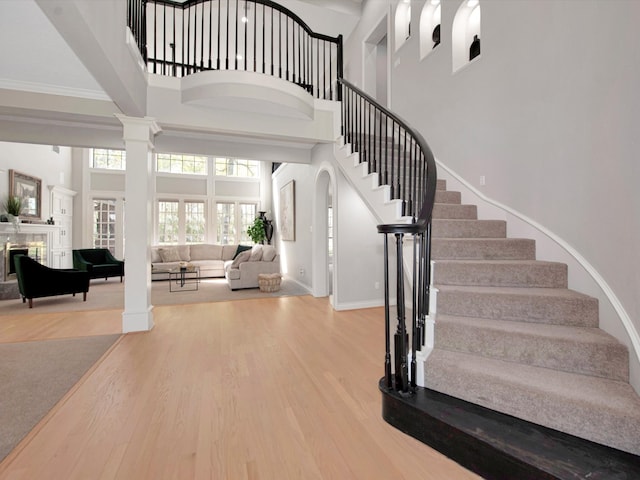 entryway with hardwood / wood-style flooring, decorative columns, crown molding, and a high ceiling