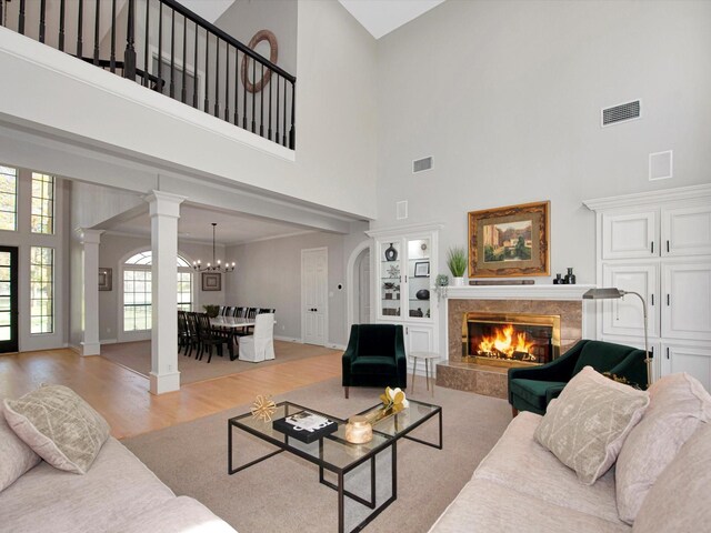 living room with a fireplace, a healthy amount of sunlight, a high ceiling, and light wood-type flooring