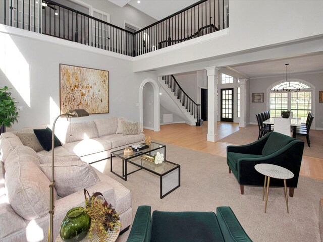 living room featuring a high ceiling, light hardwood / wood-style flooring, and ornate columns