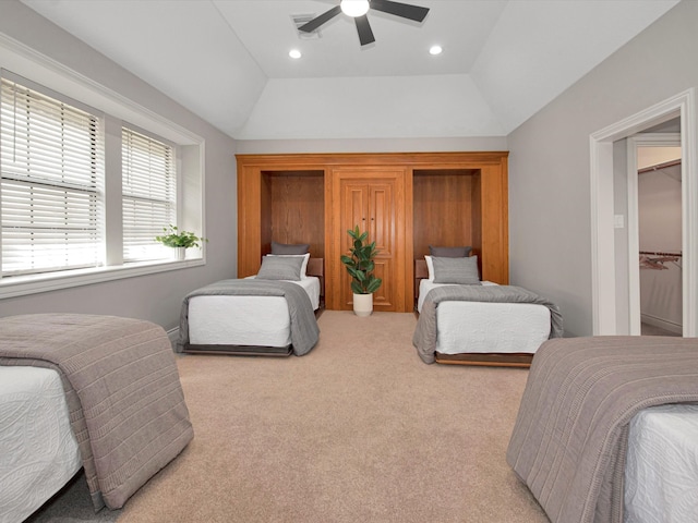 bedroom featuring light colored carpet, ceiling fan, a tray ceiling, and a walk in closet