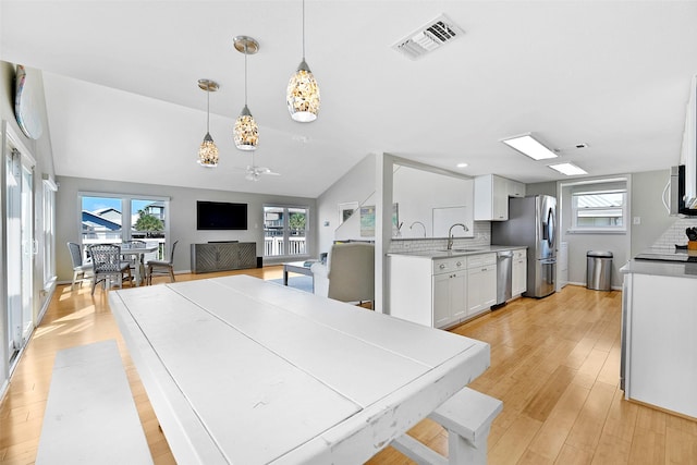 dining room featuring light wood-type flooring, visible vents, plenty of natural light, and lofted ceiling