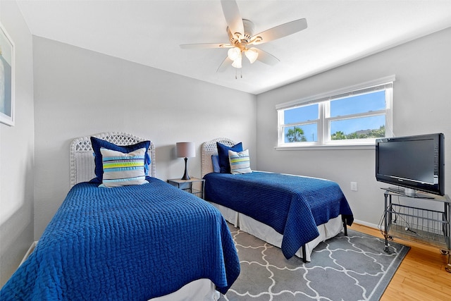 bedroom with wood finished floors, a ceiling fan, and baseboards