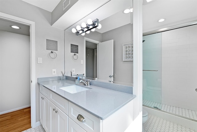 bathroom featuring hardwood / wood-style flooring, a tile shower, vanity, and toilet